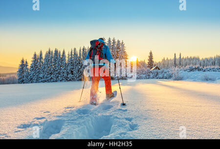 Escursioni con le racchette da neve walker in esecuzione in polvere di neve con bellissima alba luce. Outdoor attività invernali e uno stile di vita sano Foto Stock