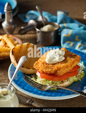 Una deliziosa casa fatta di hamburger di pesce con lattuga, pomodoro e salsa tartara. Foto Stock