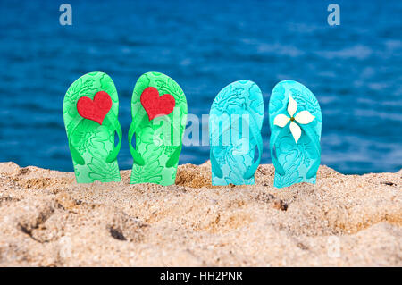 Cuore rosso su un flip-flop di un giovane nella sabbia di una spiaggia Foto Stock