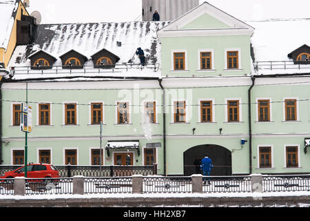 Mosca, Russia. Domenica, 15 gennaio 2017. Unidentified, irriconoscibile lavoratore pulisce il tetto del vecchio edificio. Wet, ventoso e nevoso domenica a Mosca. La temperatura è di circa -2C (28F). Nuvole pesanti, bufera di neve. Pulitori per strada e la pulizia della neve veicoli sono occupato. © Alex Immagini/Alamy Live News Foto Stock