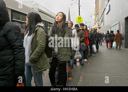 Una linea lunga su una fermata bus sulla strada principale di Chinatown, il centro cittadino di lavaggio, Queens, a New York City Foto Stock