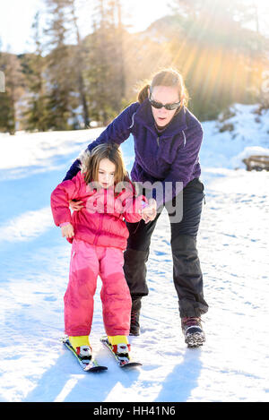 Professional istruttore di sci è di insegnare a un bambino a sciare in una giornata di sole su un pendio di montagna resort con sole e neve. Famiglia e bambini vacati attivo Foto Stock