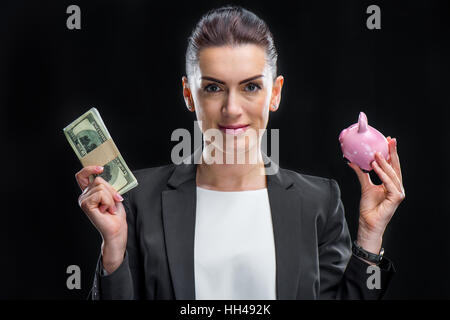 Sorridente imprenditrice azienda piggybank e dollaro banconote Foto Stock
