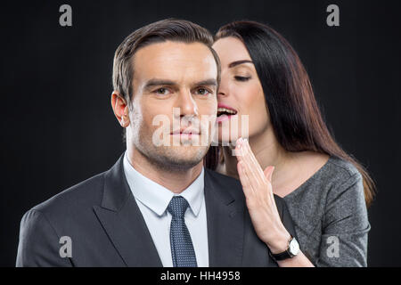 Ritratto di donna graziosa whispering in orecchio di uomo bello Foto Stock