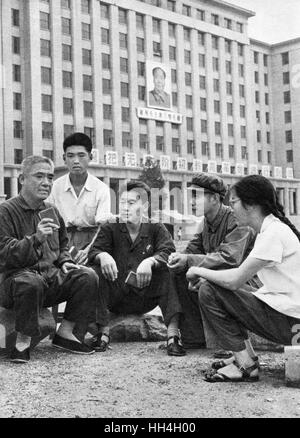 La Cina comunista - un gruppo di persone in discussione informale con un uomo più anziano (sinistra) come leader. Alcuni di loro sono holding Mao piccolo libro rosso nelle loro mani. Il presidente Mao il ritratto appeso su un edificio in background. Foto Stock