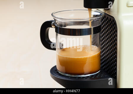 A singolo che serve caffe macchina eroga caffè espresso in un bicchiere di vetro Foto Stock