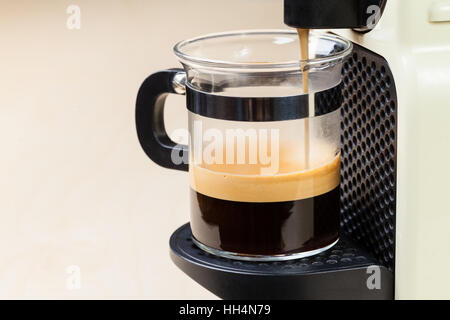 A singolo che serve caffe macchina eroga caffè espresso in un bicchiere di vetro Foto Stock