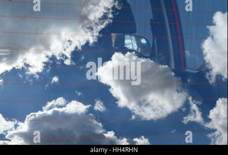 Nuvole e cielo blu riflessa in auto parabrezza posteriore, interni di auto e lo specchio appena visibile Foto Stock
