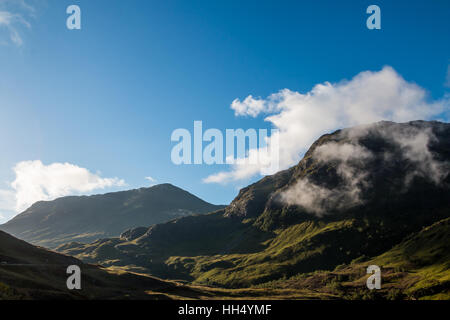 La nebbia si alza dalle montagne di Glencoe su un blu giornata soleggiata, Scozia, Agosto Foto Stock