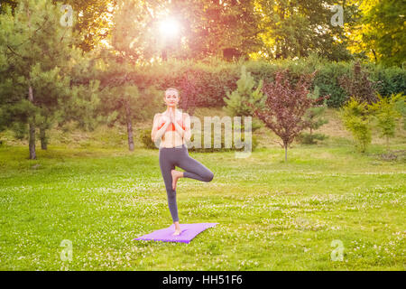 Allegro giovane bella donna pratica e in posa yoga nella East Asian park. Foto Stock