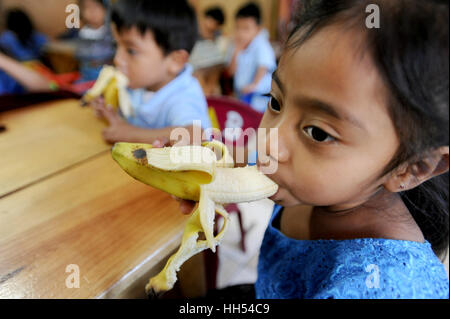 Maya bambini indigeni mangiare banana alla scuola materna a San Jorge la Laguna, Solola dipartimento in Guatemala. Foto Stock