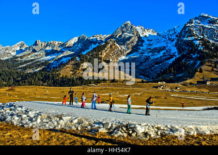 Gruppo di ragazzi practicising sci di fondo corre sul fatto di neve artificiale, La Clusaz, Alta Savoia, Francia Foto Stock