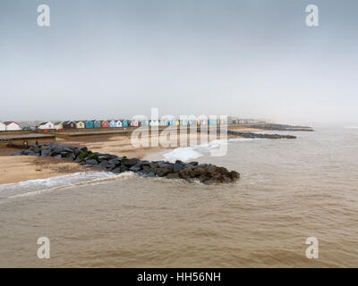 Distante misty moody immagine della spiaggia a Southwold Suffolk Inghilterra guardando indietro a la spiaggia di capanne dal molo Foto Stock