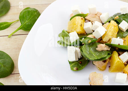 Guarnito con taglio feta insalata di spinaci, pollo e arancione sulla piastra bianca Foto Stock