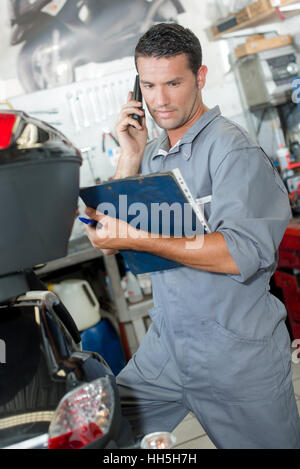 Mechanic tenendo la cartella sul telefono Foto Stock