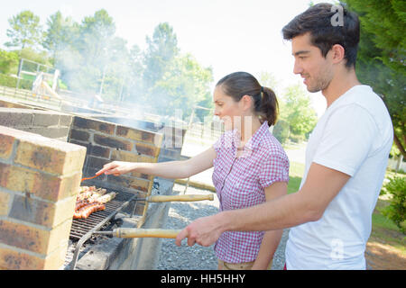 Accoppiare la preparazione di cibi cotti alla griglia su barbecue Foto Stock