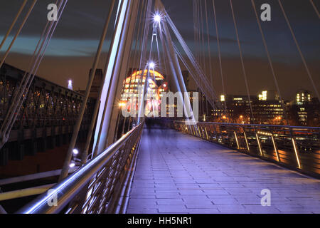 Una fotografia del piede a Hungerford Bridge come si vede dal Southbank al crepuscolo. Foto Stock