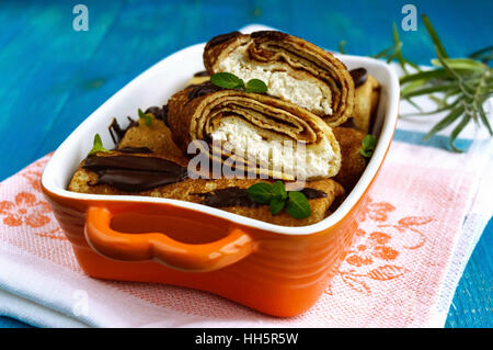 Frittelle con ricotta, cioccolato, foglie di menta decorazione su uno sfondo blu. Foto Stock