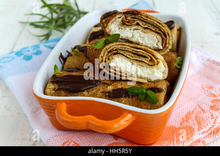 Frittelle con ricotta, cioccolato, foglie di menta decorazione su uno sfondo bianco. Foto Stock