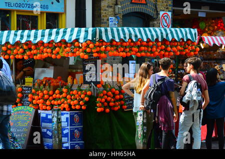 La gente in coda per scatola di cartone del succo di frutta appena spremuto a Camden Market Foto Stock