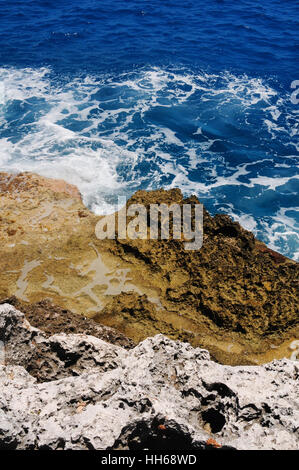 Aspre rocce coralline e reef scogliere sulle rive di Grand Cayman, Isole Cayman. Le acque turchesi del Mar dei Caraibi in background in una giornata di sole. Foto Stock