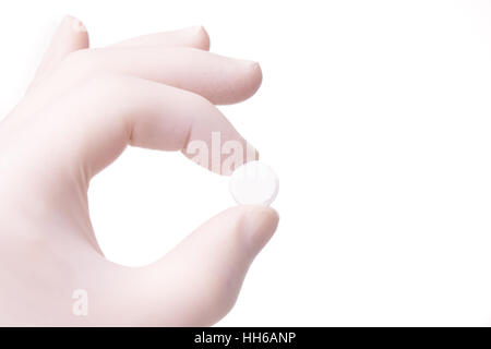 La mano guantata holding rotondo piccolo pillola. La mano e le medicine sono isolati su sfondo bianco Foto Stock