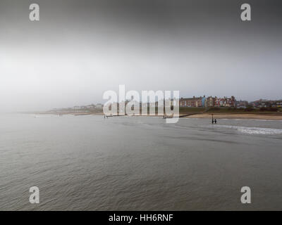 Distante misty moody immagine della spiaggia a Southwold Suffolk Inghilterra guardando indietro alla città dal molo Foto Stock