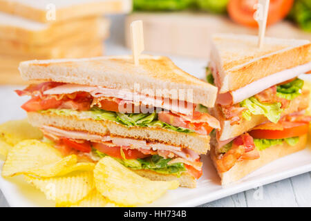 Un club sandwich su un tavolo rustico in condizioni di luce intensa. Foto Stock