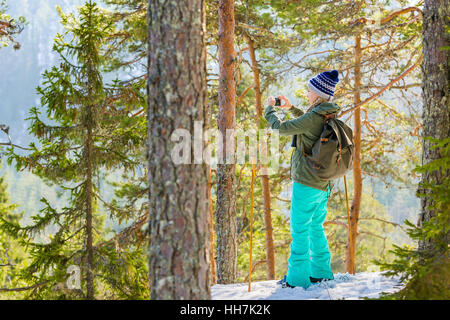 Giovane bella donna con le racchette da neve e il telefono cellulare chill out e relax nella foresta Foto Stock