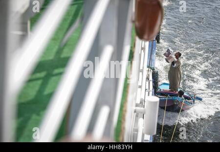 Il Cairo, Egitto. Xvii gen, 2017. Un venditore ambulante vende i propri prodotti ai turisti su una nave nel fiume Nilo d'Egitto. Quando le navi immettere Esna serrature, quei venditori ambulanti attribuirà le loro barche per la nave da funi e getta artigianato come sciarpa per i turisti a bordo. Trascinato dalla nave, essi si arresta e il resto solo dopo che i prodotti sono venduti. Credito: Yang Lei/Xinhua/Alamy Live News Foto Stock