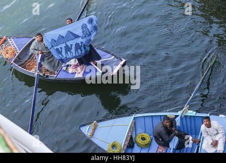 Il Cairo, Egitto. Xvii gen, 2017. Un venditore ambulante dimostra il suo prodotto per i turisti su una nave nel fiume Nilo d'Egitto. Quando le navi immettere Esna serrature, quei venditori ambulanti attribuirà le loro barche per la nave da funi e getta artigianato come sciarpa per i turisti a bordo. Trascinato dalla nave, essi si arresta e il resto solo dopo che i prodotti sono venduti. Credito: Yang Lei/Xinhua/Alamy Live News Foto Stock