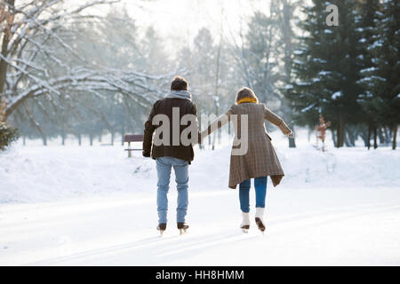 Coppia senior in inverno pieno di sole natura il pattinaggio su ghiaccio, in vista posteriore Foto Stock