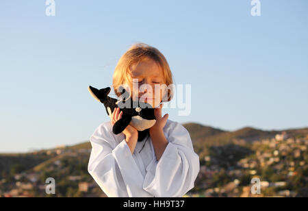 Ragazza sognante, gli occhi chiusi, sorridendo con balena giocattolo fuori nel sole risplendere Foto Stock