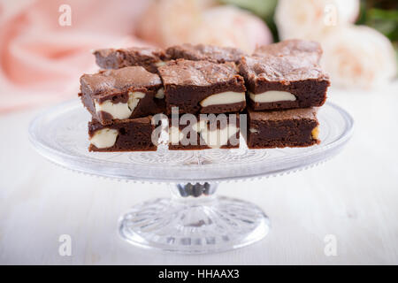 Il giorno di San Valentino cheesecake brownies sulla torta stand su le rose rosa sullo sfondo Foto Stock