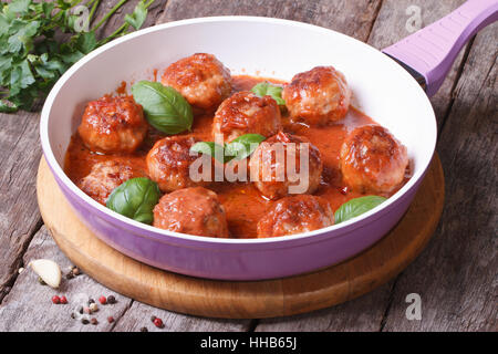 Hot le polpette di carne con salsa di pomodoro in una padella su di un tavolo di legno Foto Stock