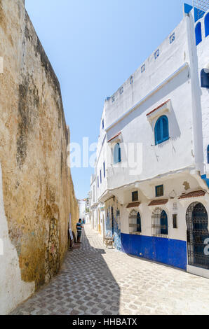 Vicolo di pietra con mura storiche della città e del blu e del bianco lavato edifici di Asilah, Marocco, Africa del Nord Foto Stock