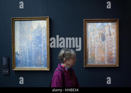 Visitatore nella parte anteriore dei due dipinti di serie La Cathedrale de Rouen (Cattedrale di Rouen) dal francese pittore impressionista Claude Monet visualizzati in Musee d'Orsay a Parigi, Francia. Il titolo completo del dipinto a sinistra: la cattedrale di Rouen. Facciata e Tour d'Albane nella mattina Sun. in armonia in bianco (1892-1893). Il titolo completo del dipinto a destra: Cattedrale di Rouen. Facciata in mattinata Sun. armonia in blu (1892-1893). Foto Stock