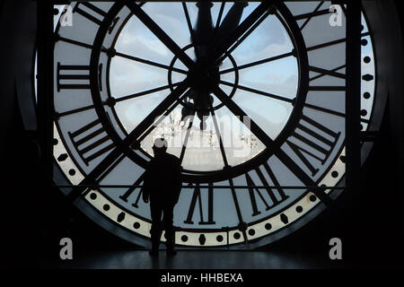 Il visitatore si affaccia il pensiero del grande vetro orologio al Musée d'Orsay a Parigi, Francia. Basilica del Sacro Cuore a Montmartre (Basilique du Sacre-Coeur de Montmartre) è visto in background. Foto Stock