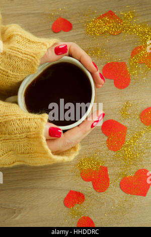 Tazza di caffè o di tè nella donna con le mani buona manicure rosso in felpa lavorata a maglia Foto Stock