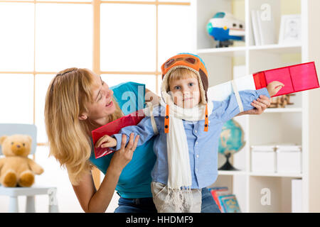 Kid boy vestito come un pilota con ali giocattolo giocare in casa Foto Stock