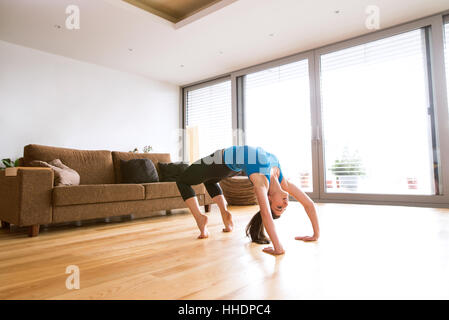 Giovane donna che esercitano a casa, stretching, facendo ponte posa. Foto Stock