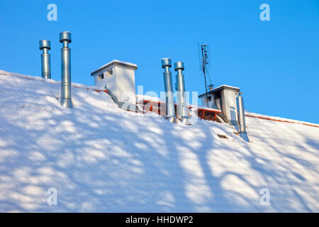Camino sulla coperta di neve tetto in inverno. Foto Stock
