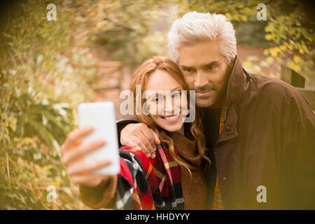 Giovane costeggiata tenendo selfie con la fotocamera del telefono in giardino Foto Stock