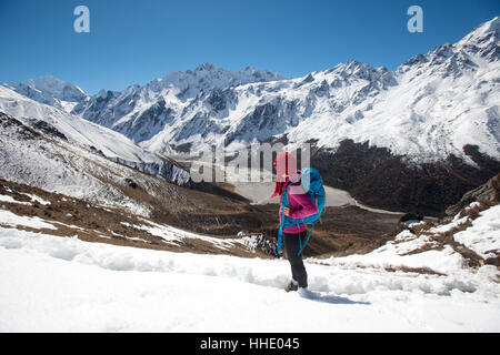 Una ragazza sondaggi il Langtang valley dalla sommità del Kyanjin Ri con il picco di Ganchempo nella distanza, Langtang Valley, Nepal Foto Stock
