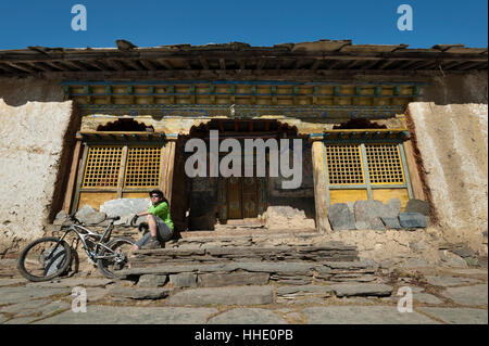 Un mountain biker prende un meritato riposo a Mu Gompa, l'ultimo villaggio della valle Tsum, Nepal Foto Stock