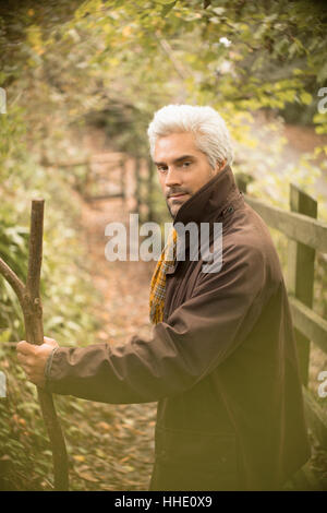 Ritratto serio uomo con bastone da passeggio sul percorso di autunno Foto Stock