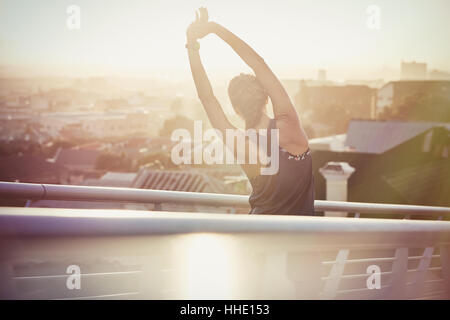 Guida femmina bracci di estensione sulla passerella urbano di sunrise Foto Stock