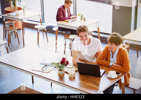 La gente di affari di bere il caffè riunione tramite computer portatile in cafe Foto Stock