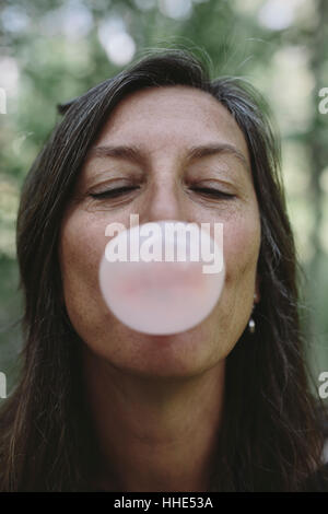 Ritratto di donna di mezza età soffiando bubble gum bubble Foto Stock