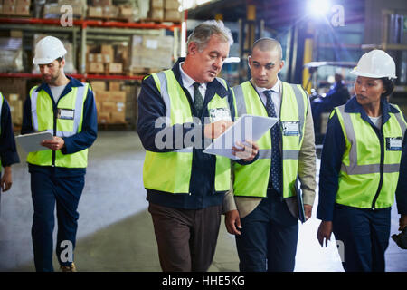 Mangiatoia e dei lavoratori con appunti parlando in magazzino di distribuzione Foto Stock